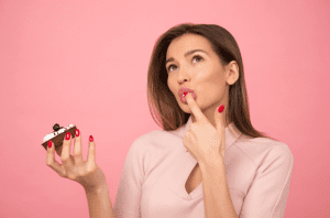 meijer cakes: woman eating-cupcake-while-standing-near-pink background inside room