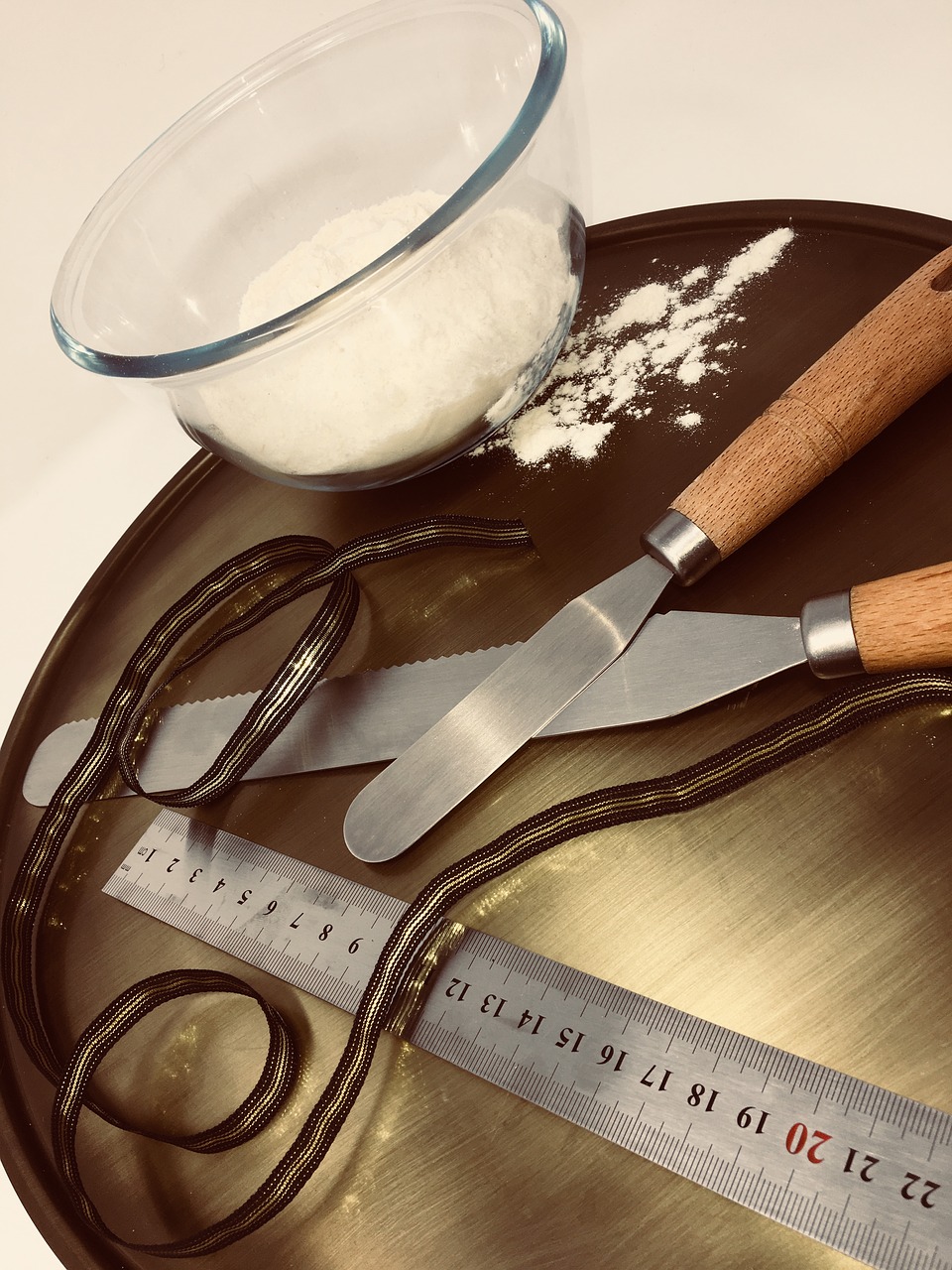 flour in a bowl with spatulas, ruler and cake board for cake decoration tools